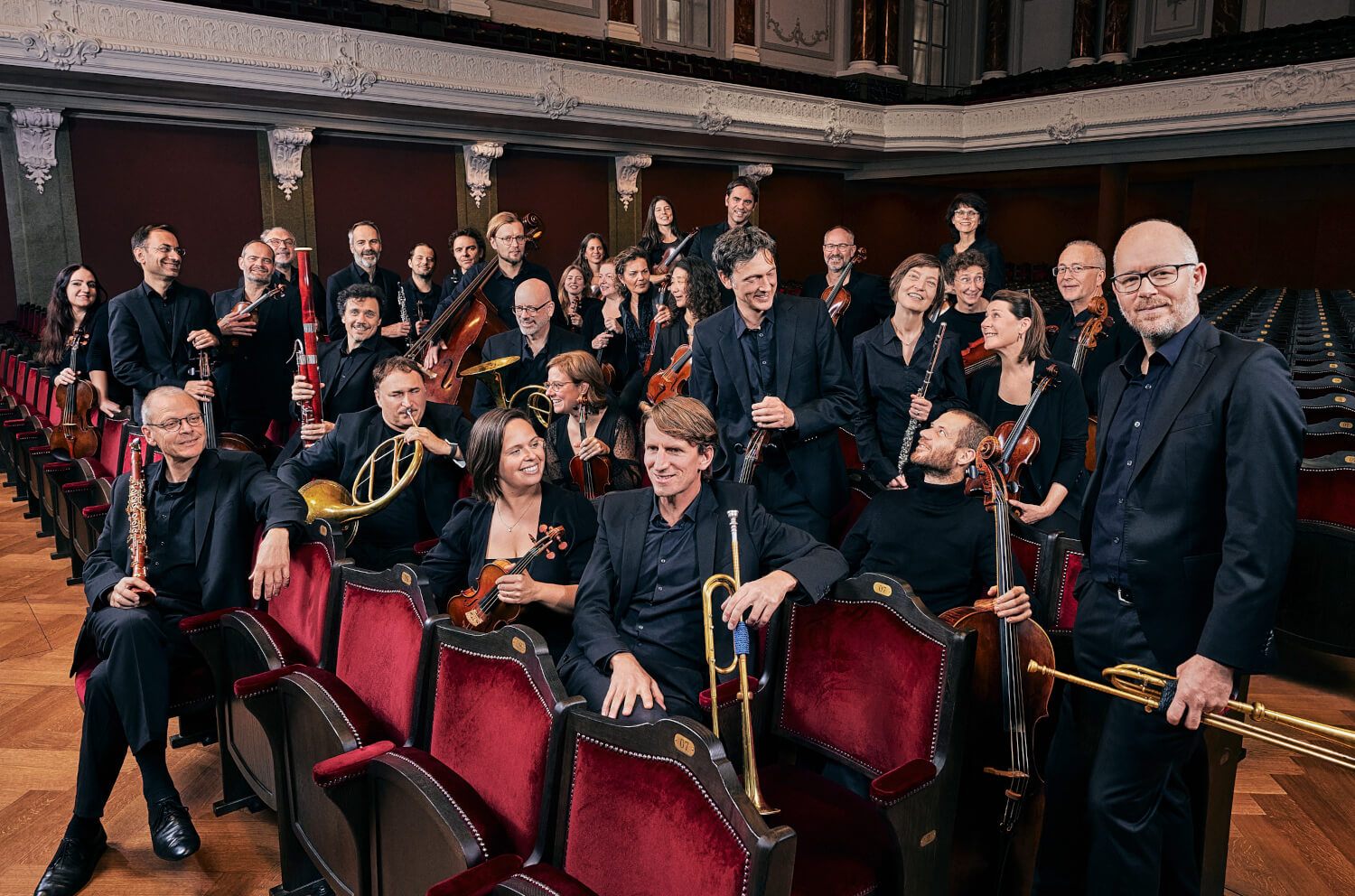 Orchesterfoto: Alle Musiker:innen des Kammerorchester Basel sitzen oder stehen mit Ihren Instrumenten im Publikumsbereich des Stadtcasino Basel Orchesterfoto: Alle Musiker:innen des Kammerorchester Basel sitzen oder stehen mit Ihren Instrumenten im Publikumsbereich des Stadtcasino Basel