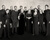 Chorbild des Collegium Vocale Gent. Auf dem Bild sind die Chormitglieder zu sehen, sie stehen vor einer Betonwand.