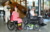 zwei Darsteller:innen im Rollstuhl, dahinter ein schick gekleideter Mann mit Blumenstrauss
