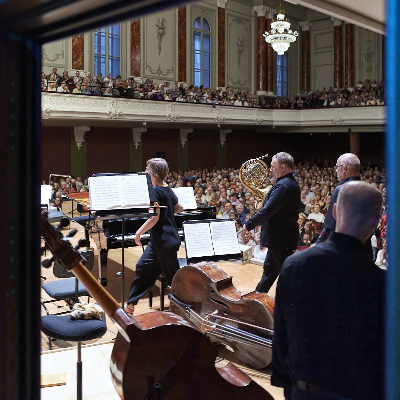 Musicians enter the stage of the Stadtcasino from the musicians’ perspective, with the audience in the background