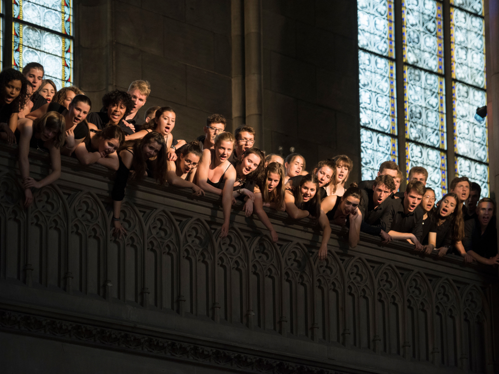Saenger:innen lehnen ueber die Balustrade