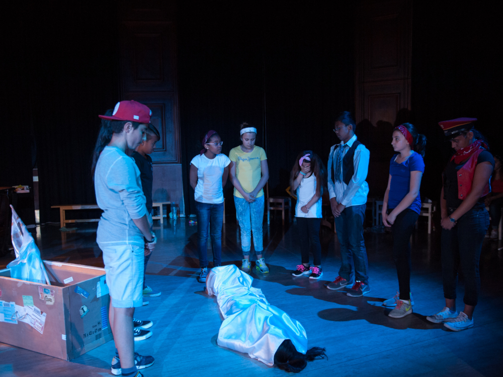 junge Schauspieler:innen stehen trauernd um eine zugedeckte Person am Boden