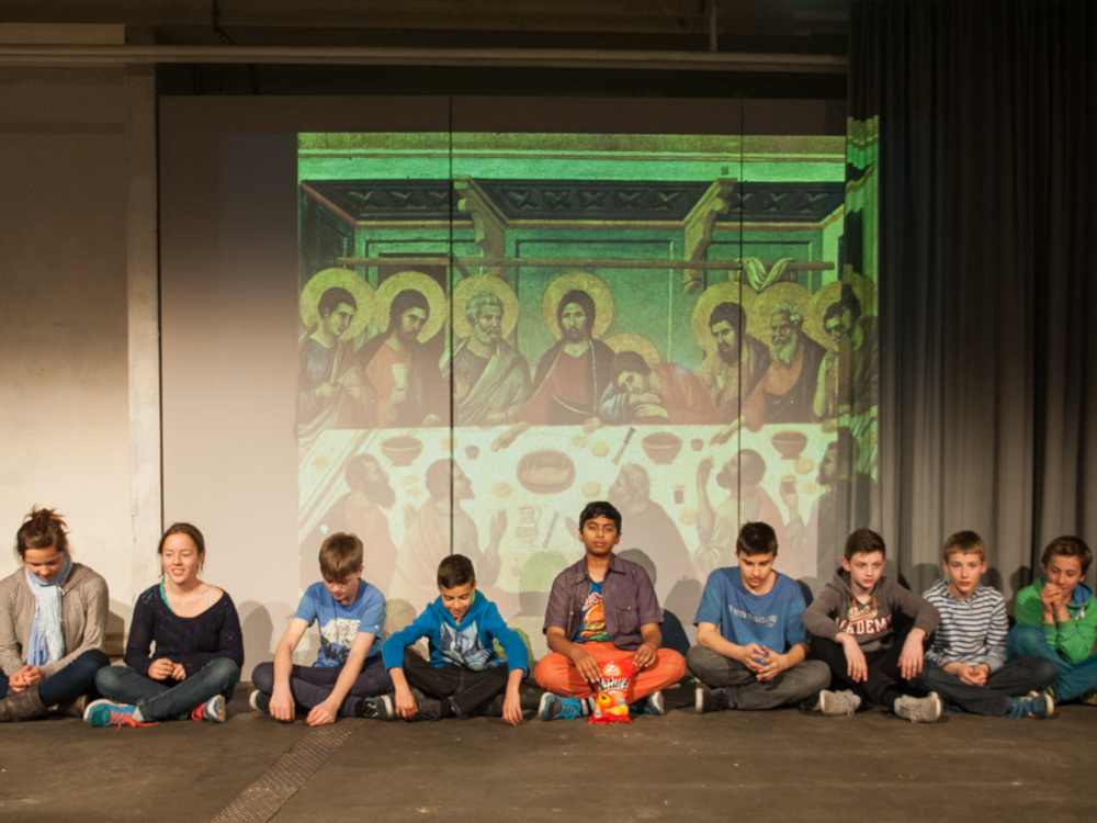 Kinder sitzen vor dem Bild des letzten Abendmahls