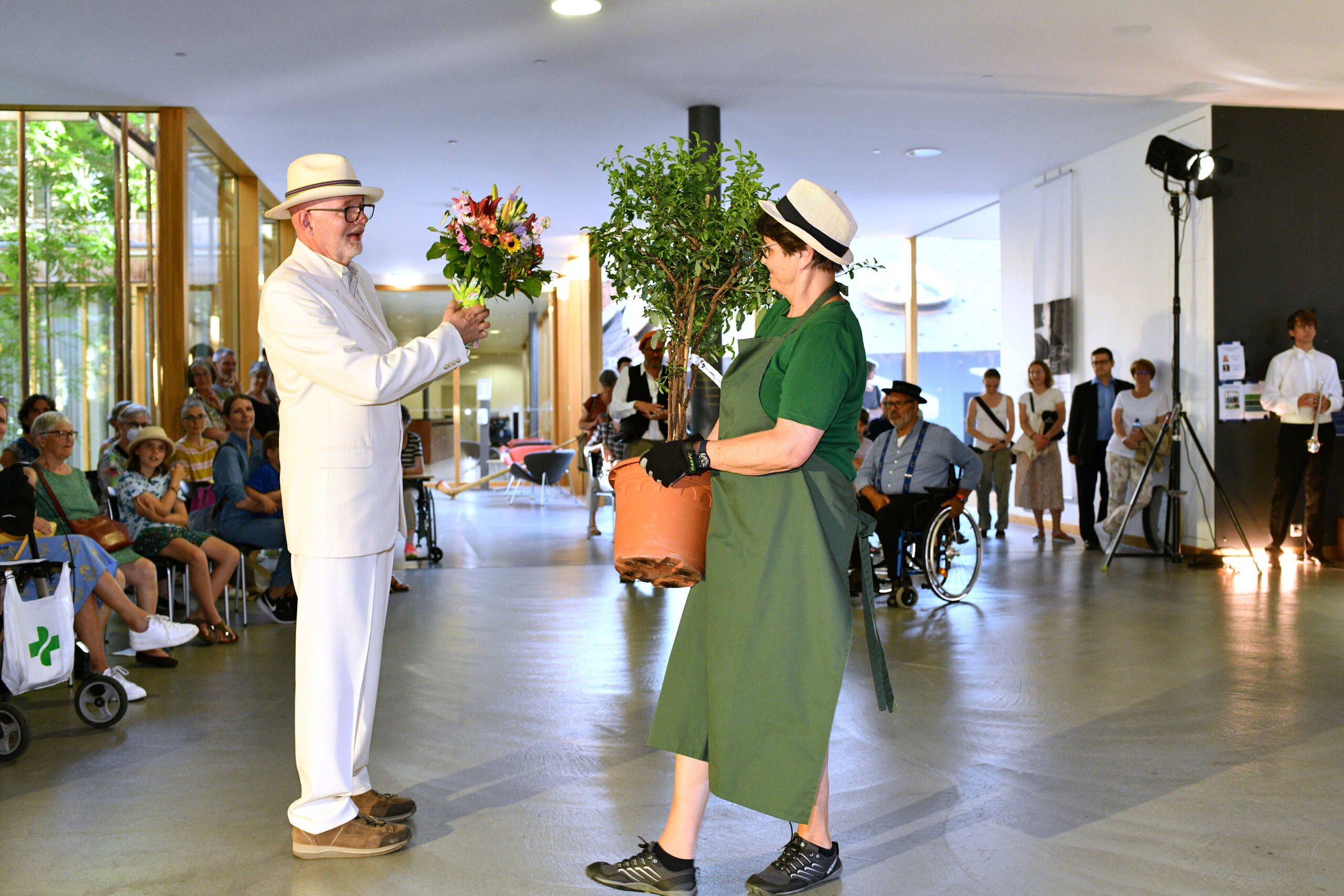 Darsteller mit Blumenstrauss, Darstellerin mit Baeumchen in einem Topf