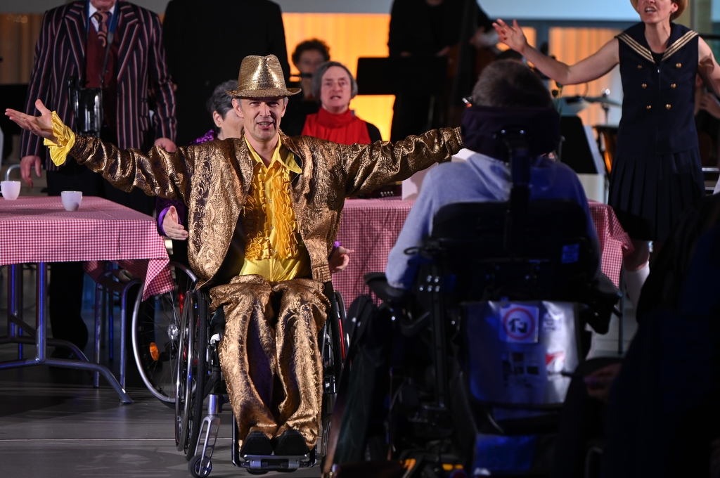 Darsteller im Rollstuhl und goldenem Kostüm präsentiert ein Wundermittel