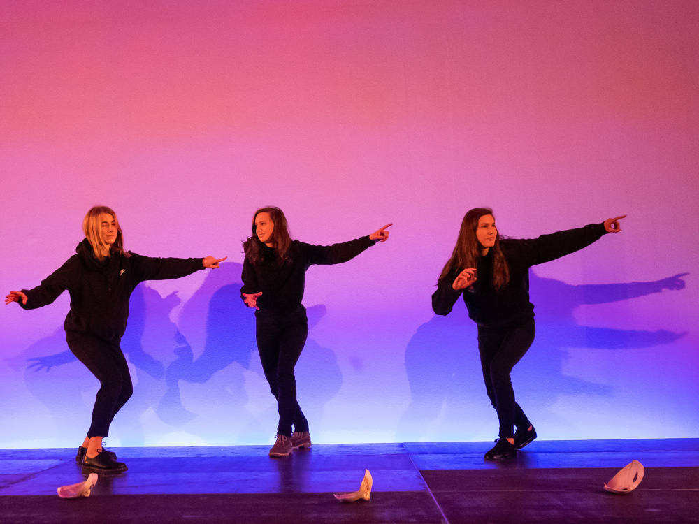 drei Maedchen bewegen sich vor einer Schattenwand