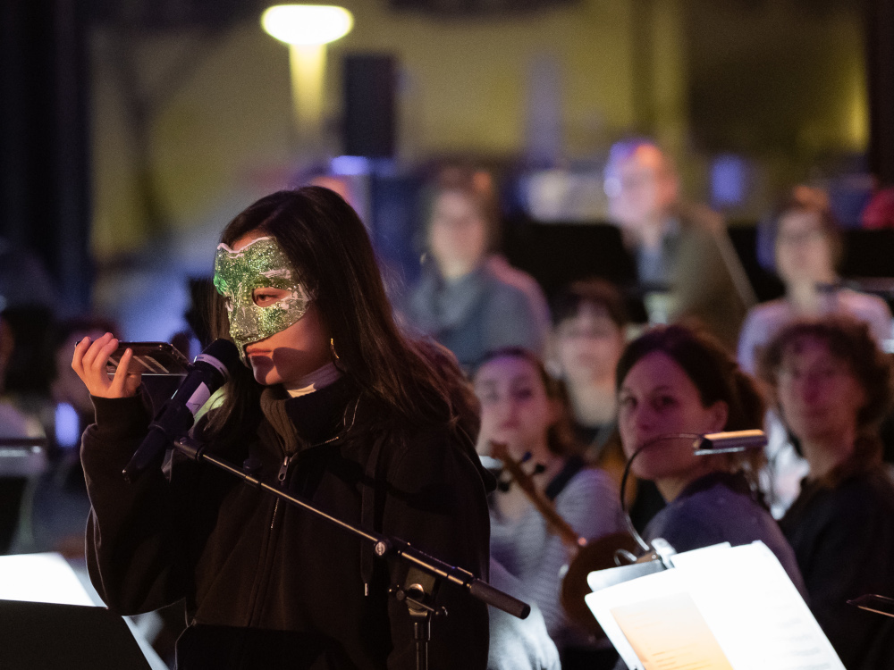 junge Saengerin mit Maske steht bei einem Mikrophon