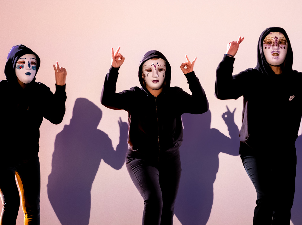 drei Maedchen mit Maske vor einer Schattenwand