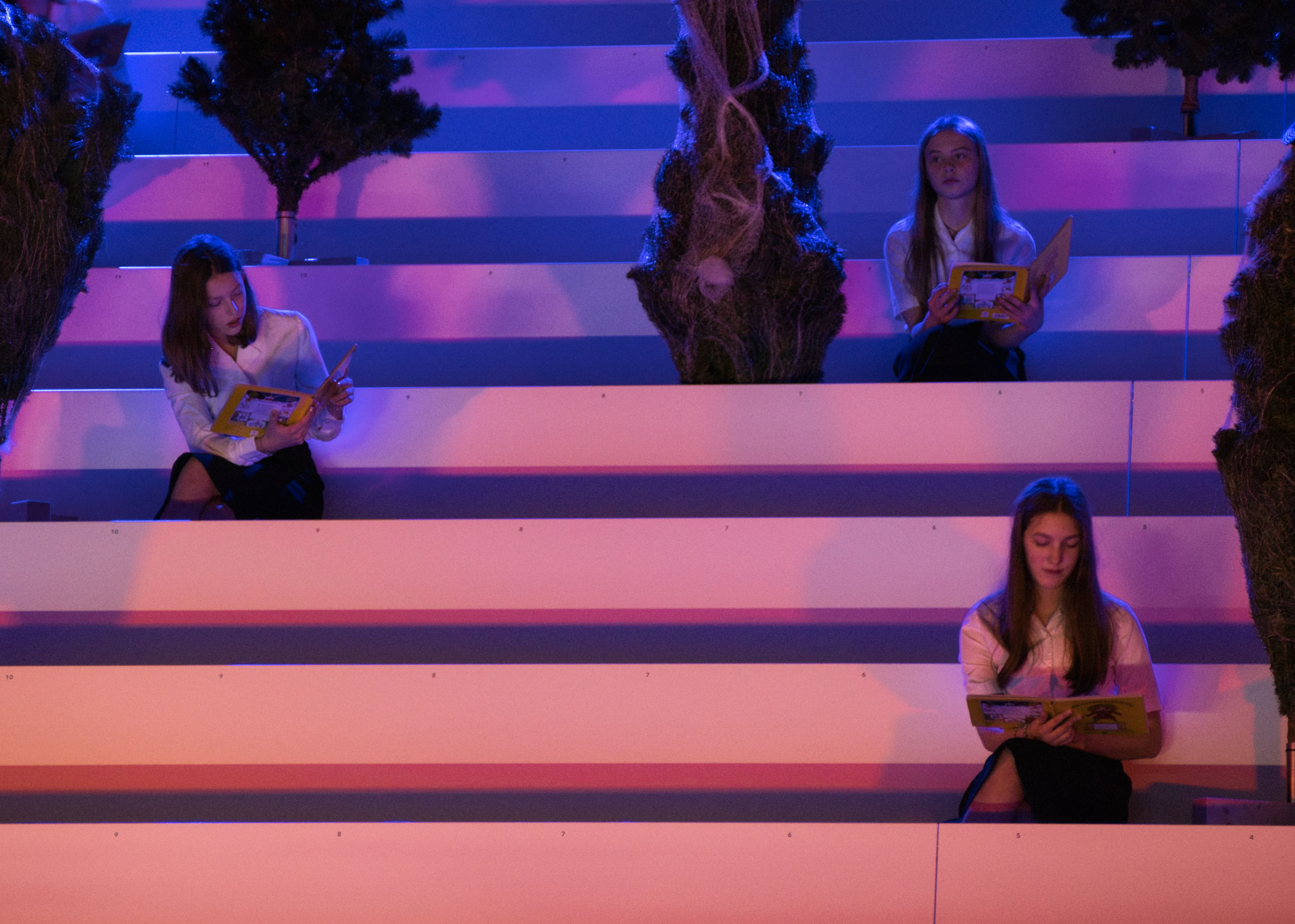 Drei Frauen sitzen auf einer Empore, sie schauen in ein Buch.