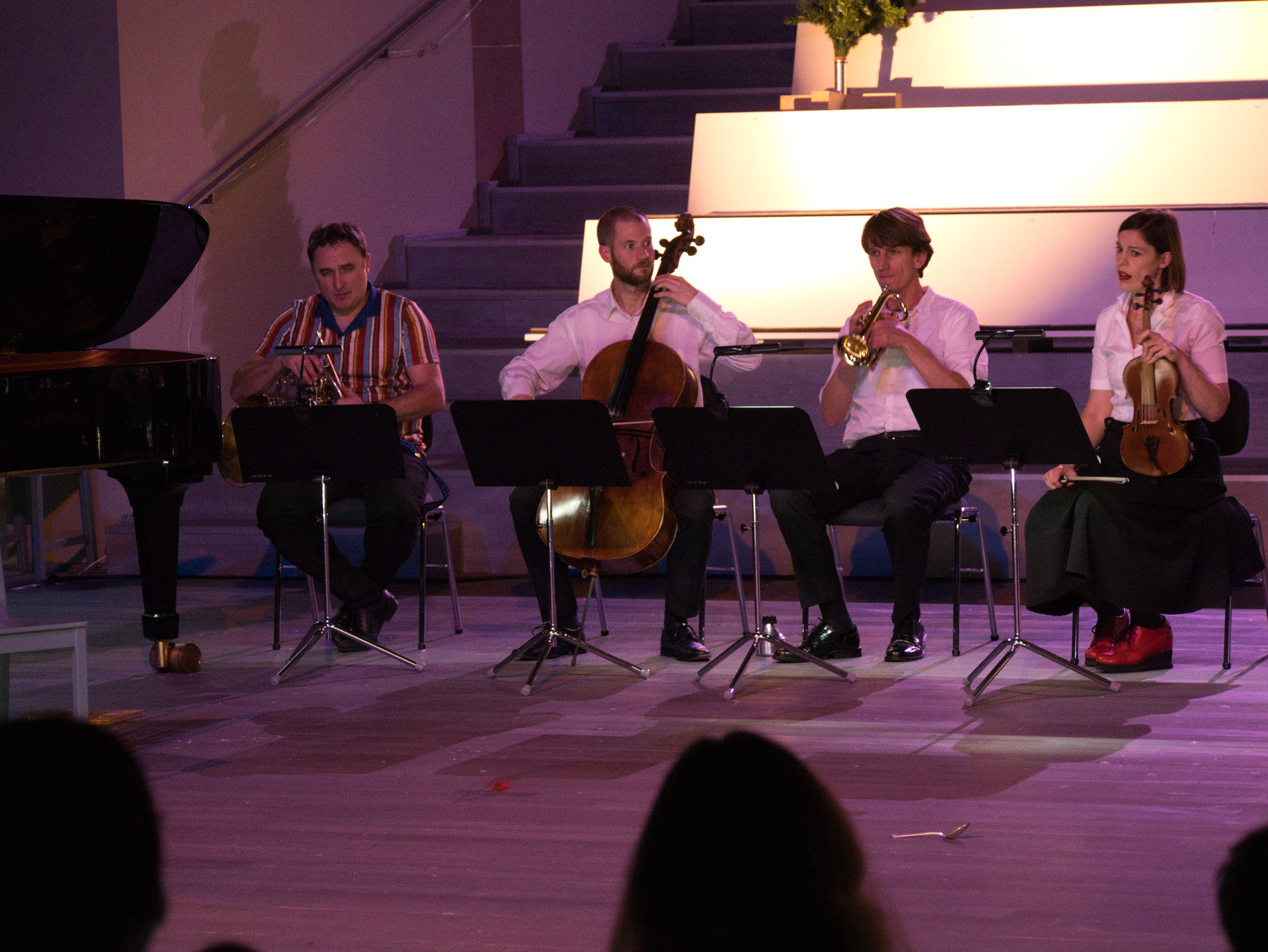 Vier Musiker:innen sitzen in einer Reihe und musizieren.