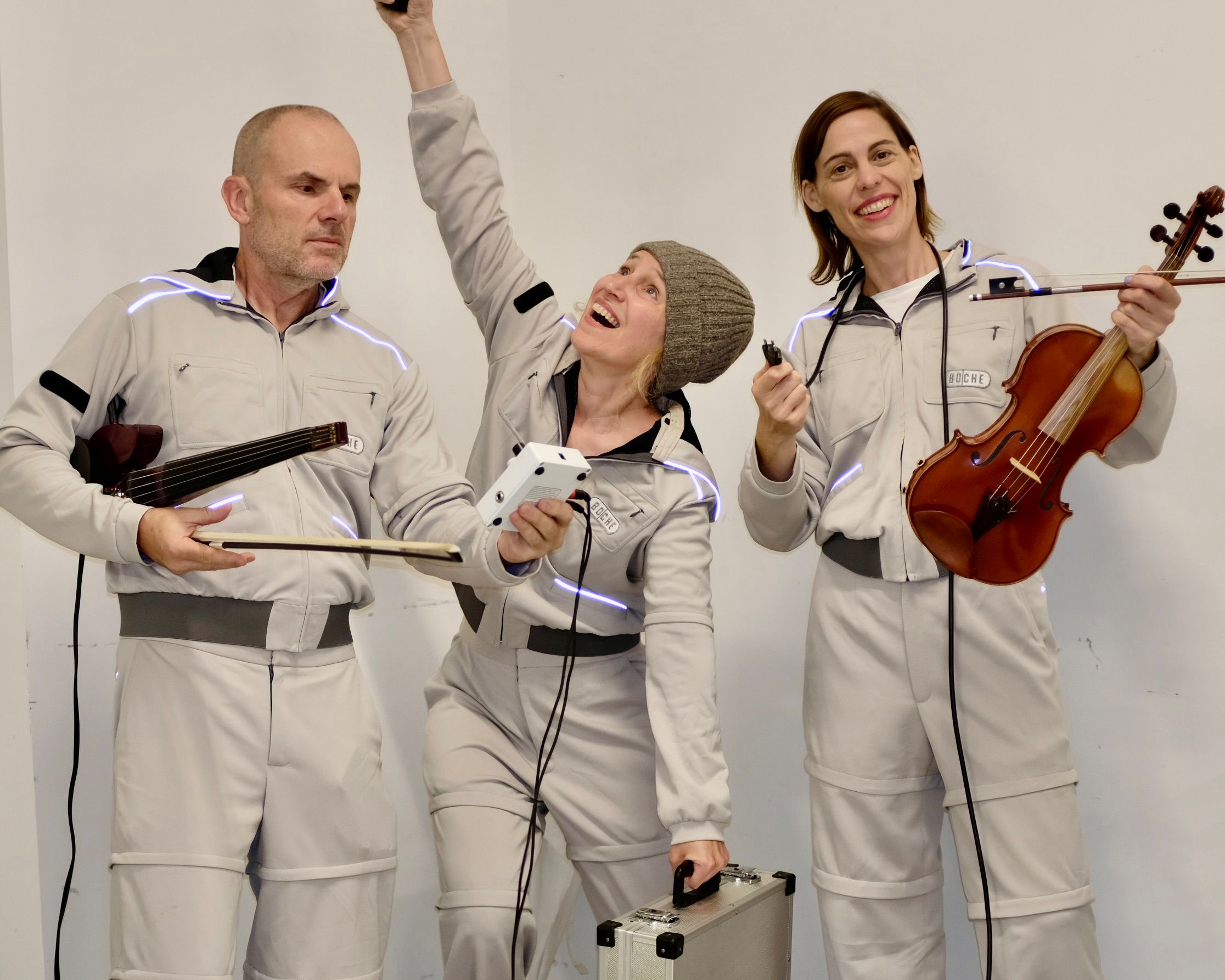 Drei Musiker:innen in Anzügen vor der Kamera