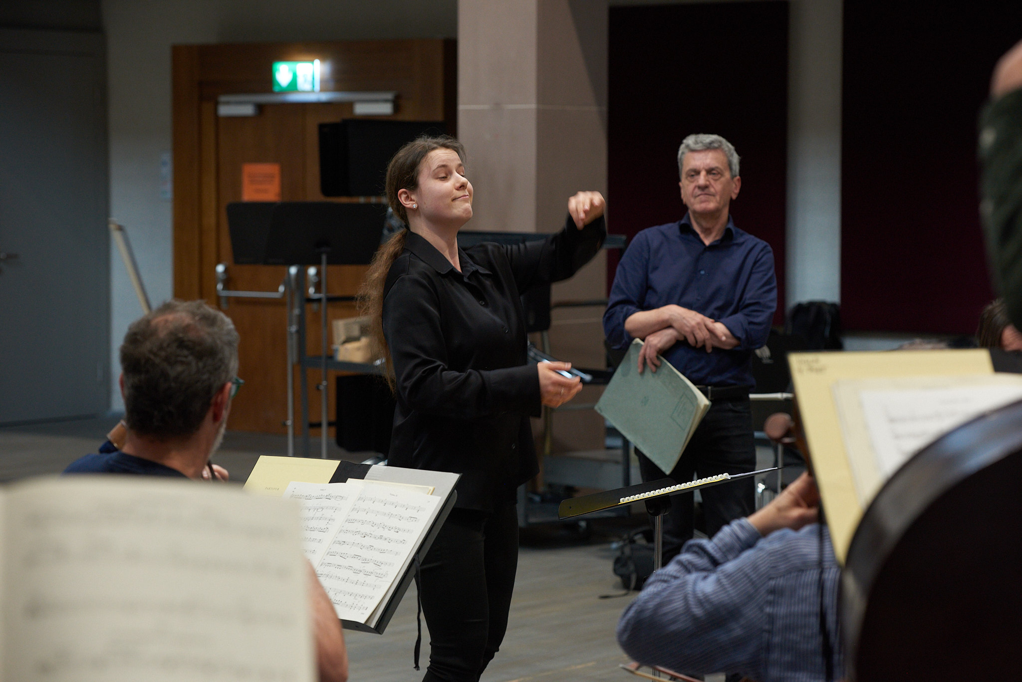 Junge Dirigentin vor einem Orchester.