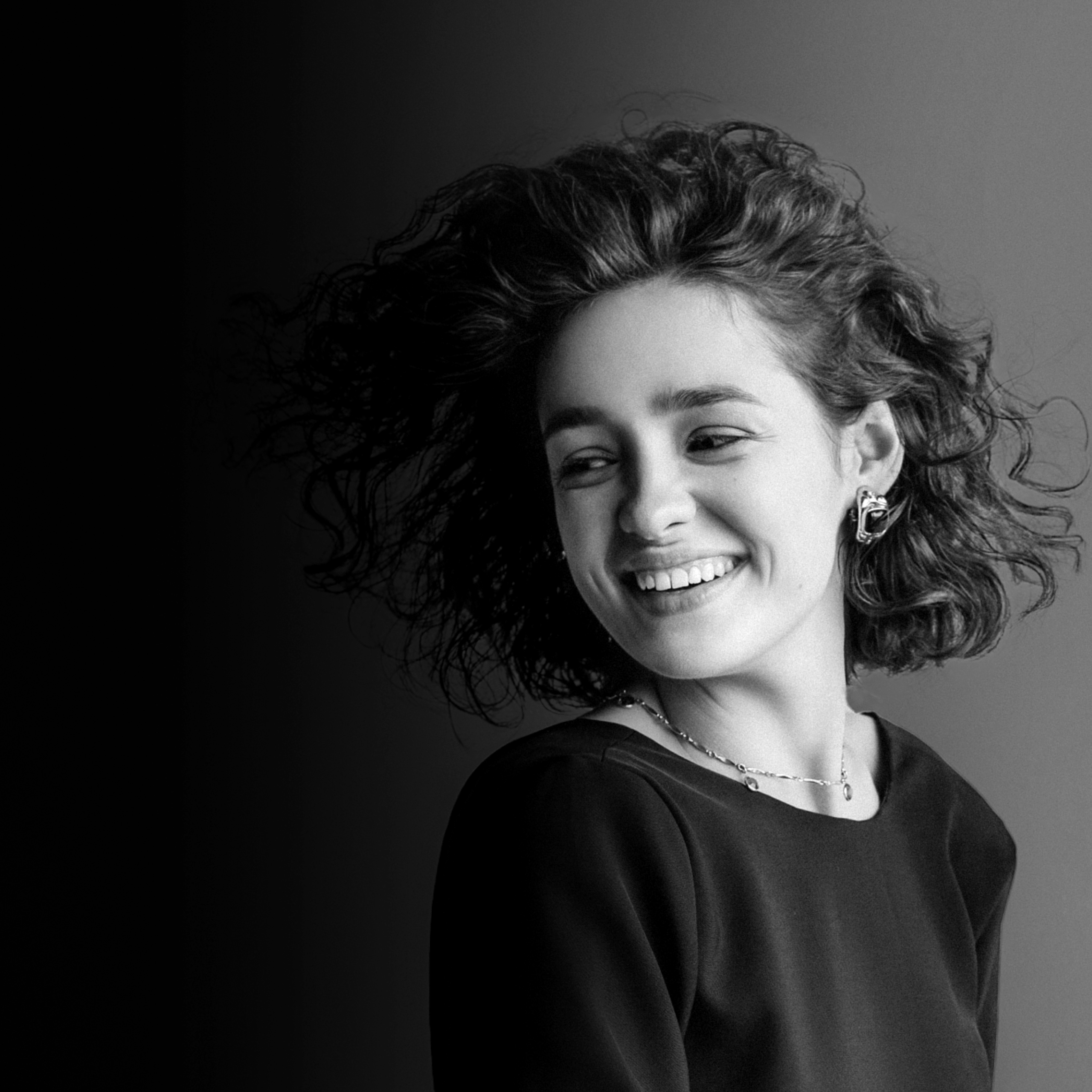 Portrait von der Cellistin Anastasia Kobekina. Sie lacht und schaut dabei seitlich nach unten.