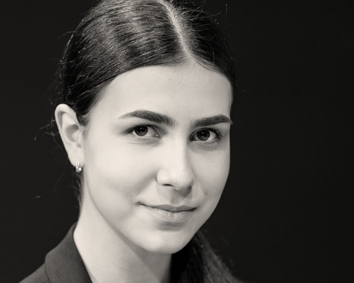 Portrait von Alexandra Dovgan. Sie hat ihre Haare zusammengebunden und blickt in die Kamera.