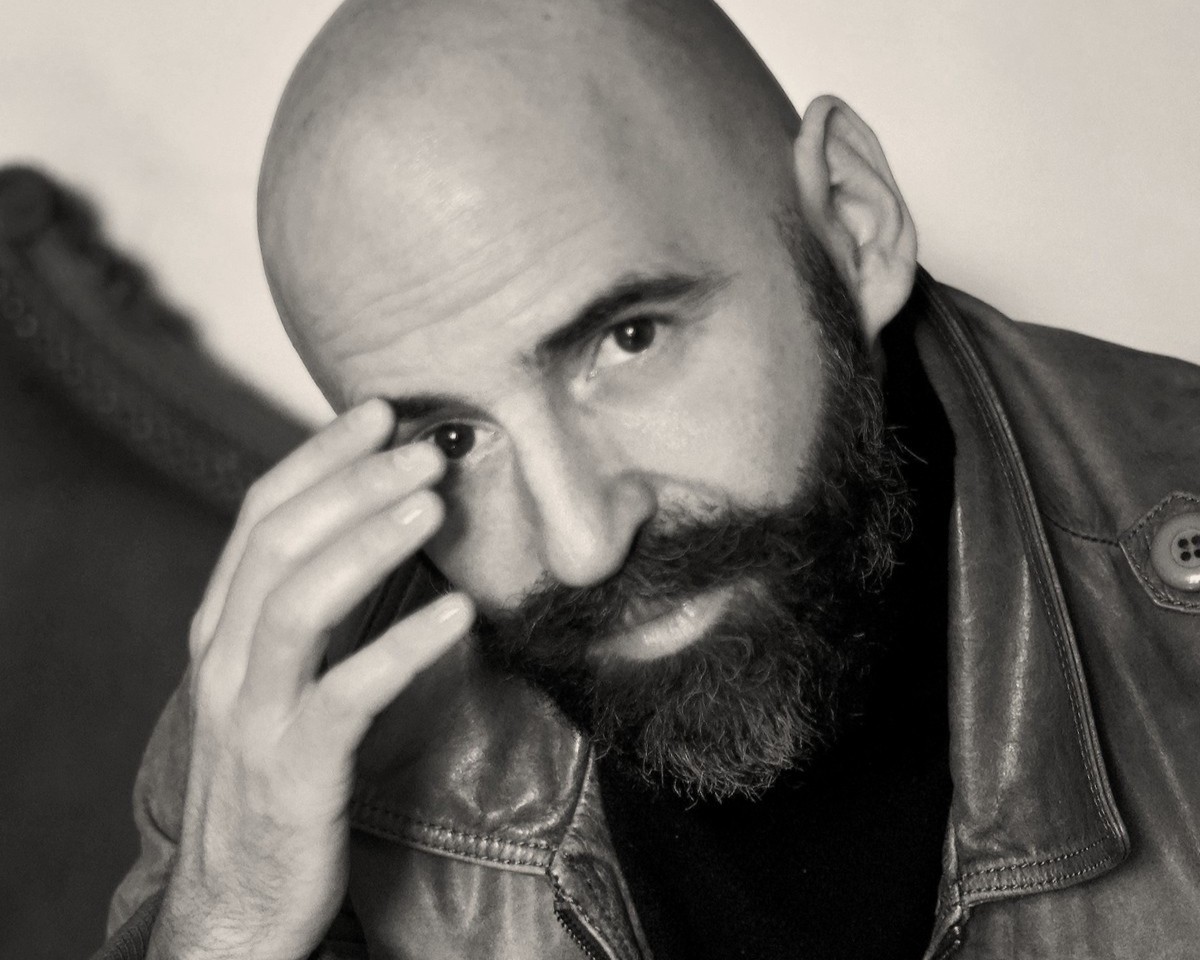 Portrait von Pierre Bleuse. Er stützt seinen Kopf auf seine Hand auf.