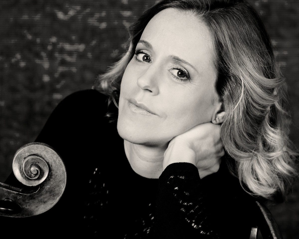 Portrait von Sol Gabetta. Sie lehnt neben ihrem Cello und blickt in die Kamera.