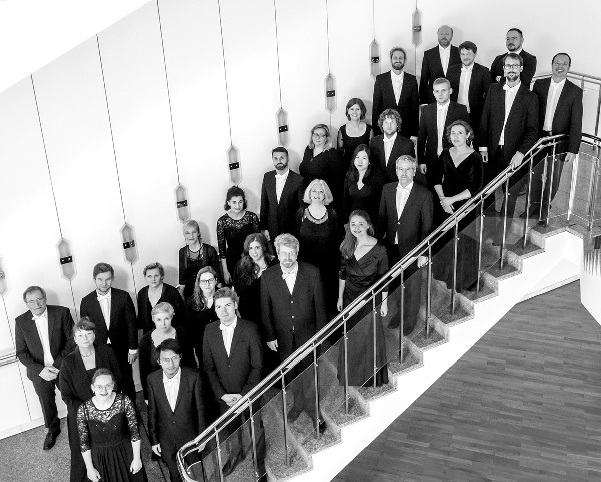 Chorfoto der Gaechinger Cantorey. Die Musiker:innen stehen auf einer Treppe und blicken in die Kamera.