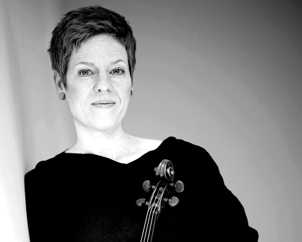 Portrait der Violinistin Isabelle Faust. Sie hält ihre Violine vor sich.