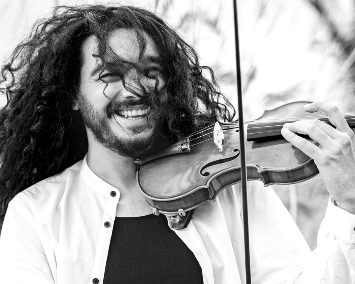 Portrait des Violinisten Nemanja Radulovic. Er spielt Geige und trägt seine langen Haare offen.