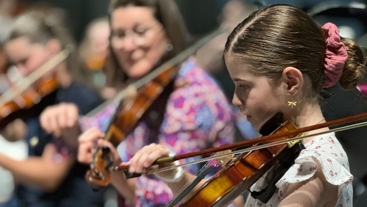 Junge Geigerin spielt ihr Instrument im Orchester.