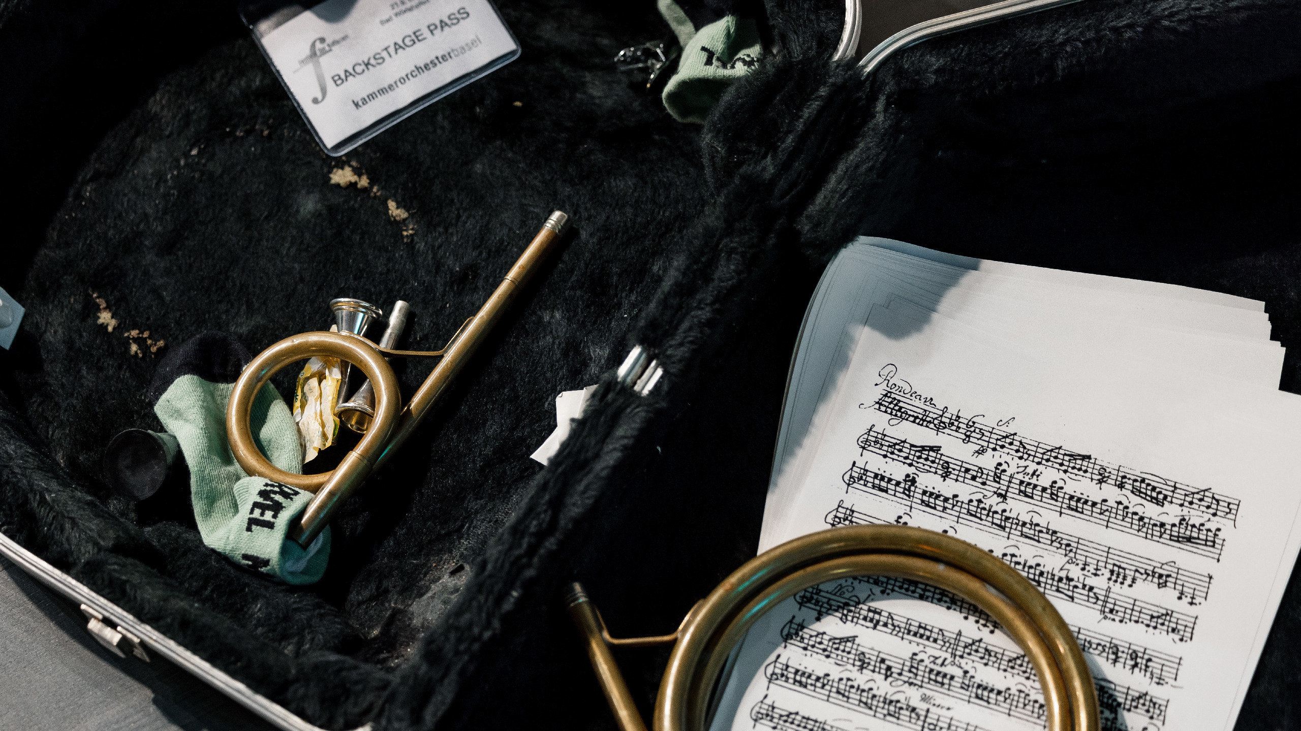 Der Instrumentenkasten eines Hornisten mit Instrumententeilen und Noten.