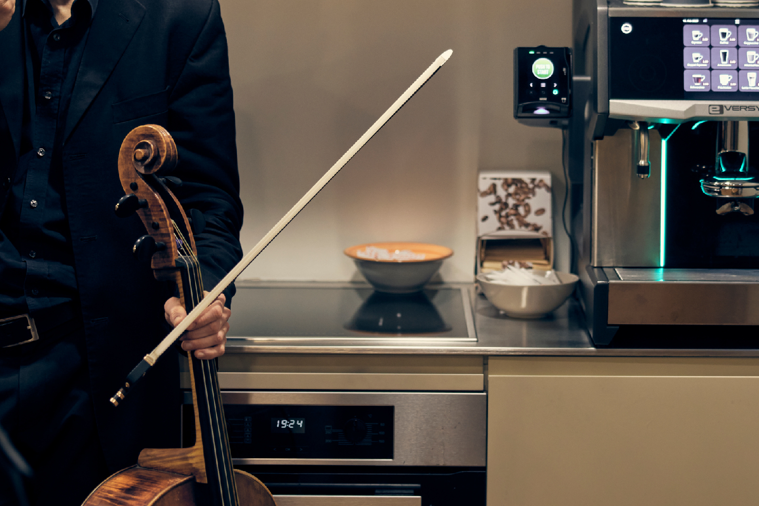 Detailbild: Ein Cellist steht backstage vor der Kuechenzeile.