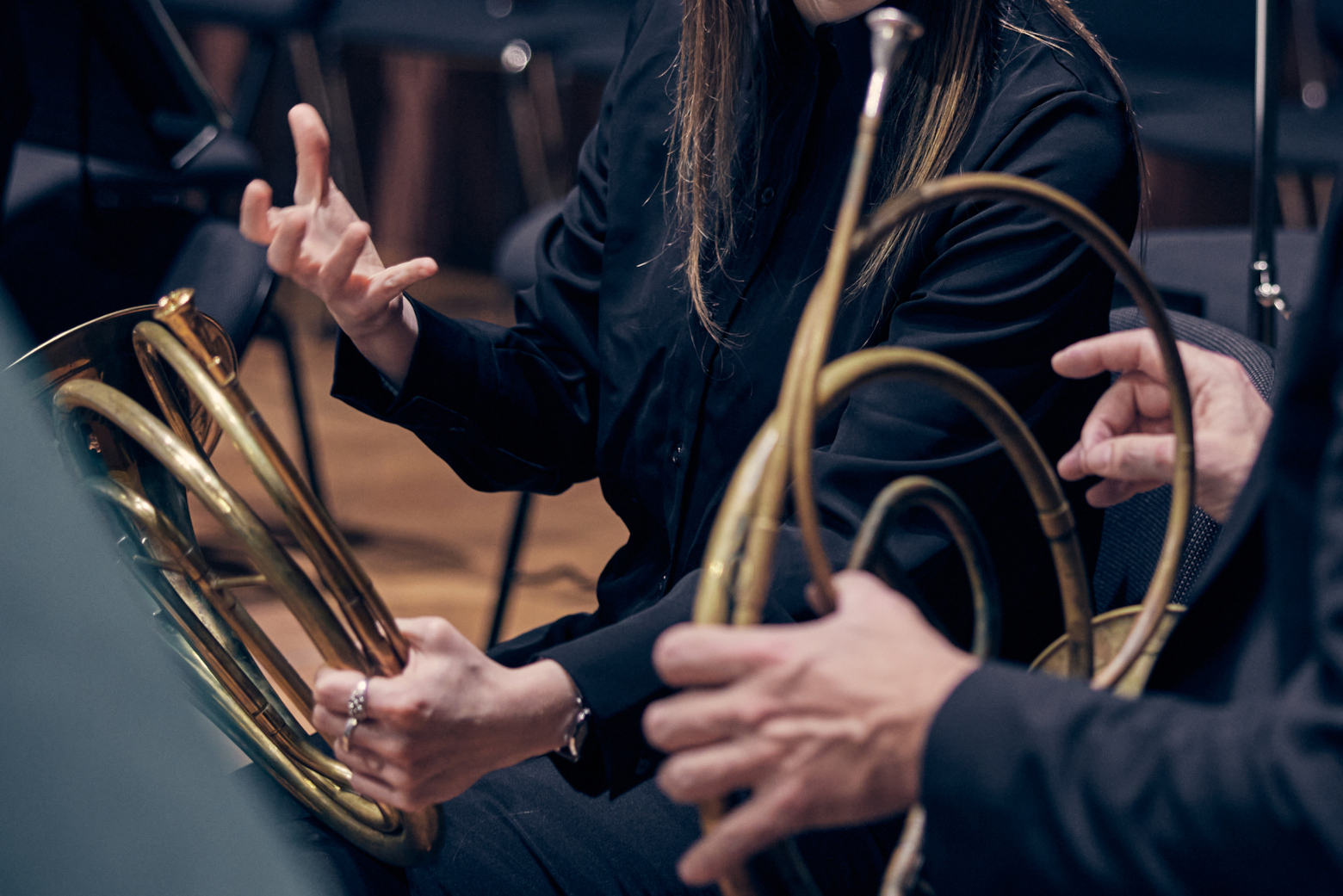Detailbild: die Haende und Instrumente zweier Hornist:innen