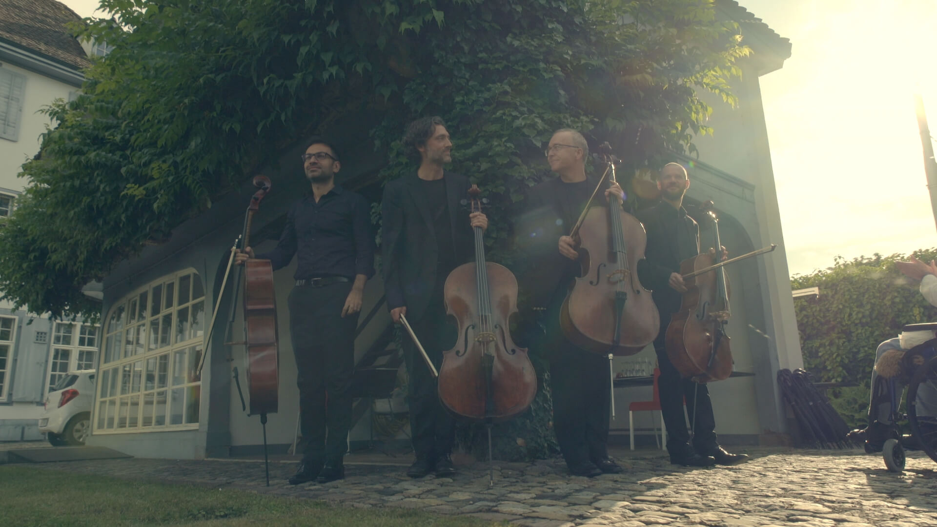 Vier Cellisten stehen mit ihren Instrumenten auf einem Platz in der Stadt und nehmen Applaus entgegen.