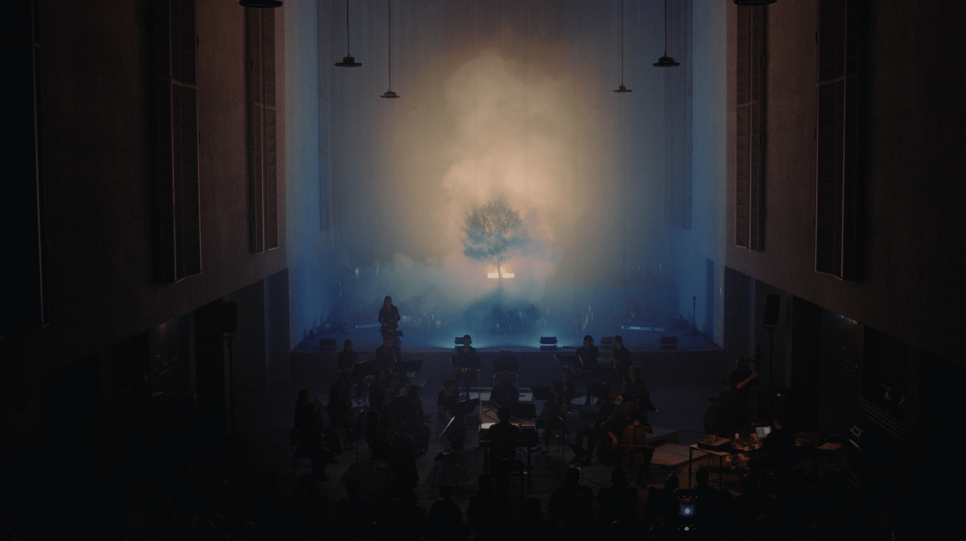 Konzertatmosphäre mit Lichteffekten, ein Baum steht im Nebel.