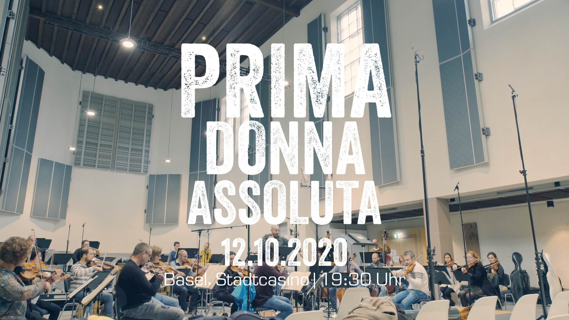 Das Orchester bei einer Probe. Eingeblendet der Text: Prima Dona Assoluta, 12.10.2020 Basel, Stadtcasino, 19.30 Uhr
