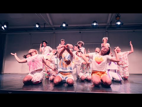 Junge Darsteller:innen posieren als Gruppe auf der Bühne.