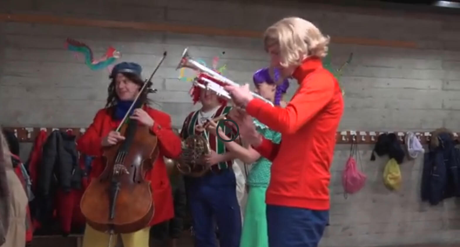Vier Musiker:innen stehen verkleidet und mit ihren Instrumenten in einem Schulhausflur.